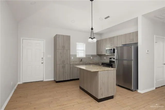 a kitchen with stainless steel appliances granite countertop a refrigerator a sink and a stove