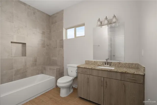 a bathroom with a granite countertop sink a toilet and bathtub