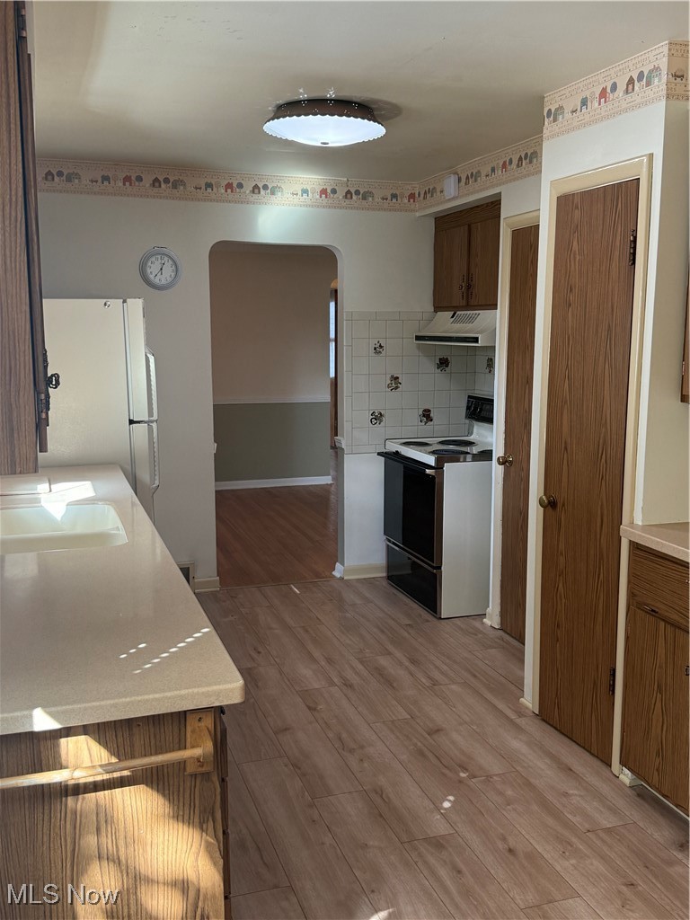 1284 Haverston Road Lyndhurst, OH 44124 - Photo 22 of 43 Kitchen with arched walkways, light wood finished floors, range, light countertops, and backsplash