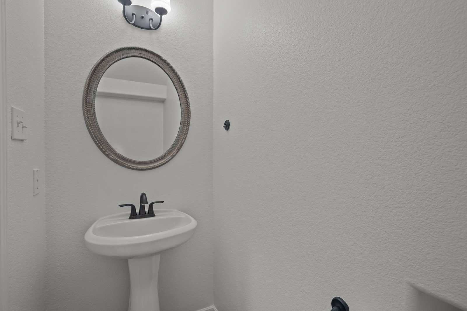 245 Razzmatazz Trail Buda, TX 78610 - Photo 31 of 37 Pedestal sink with matte black faucet and a framed oval mirror