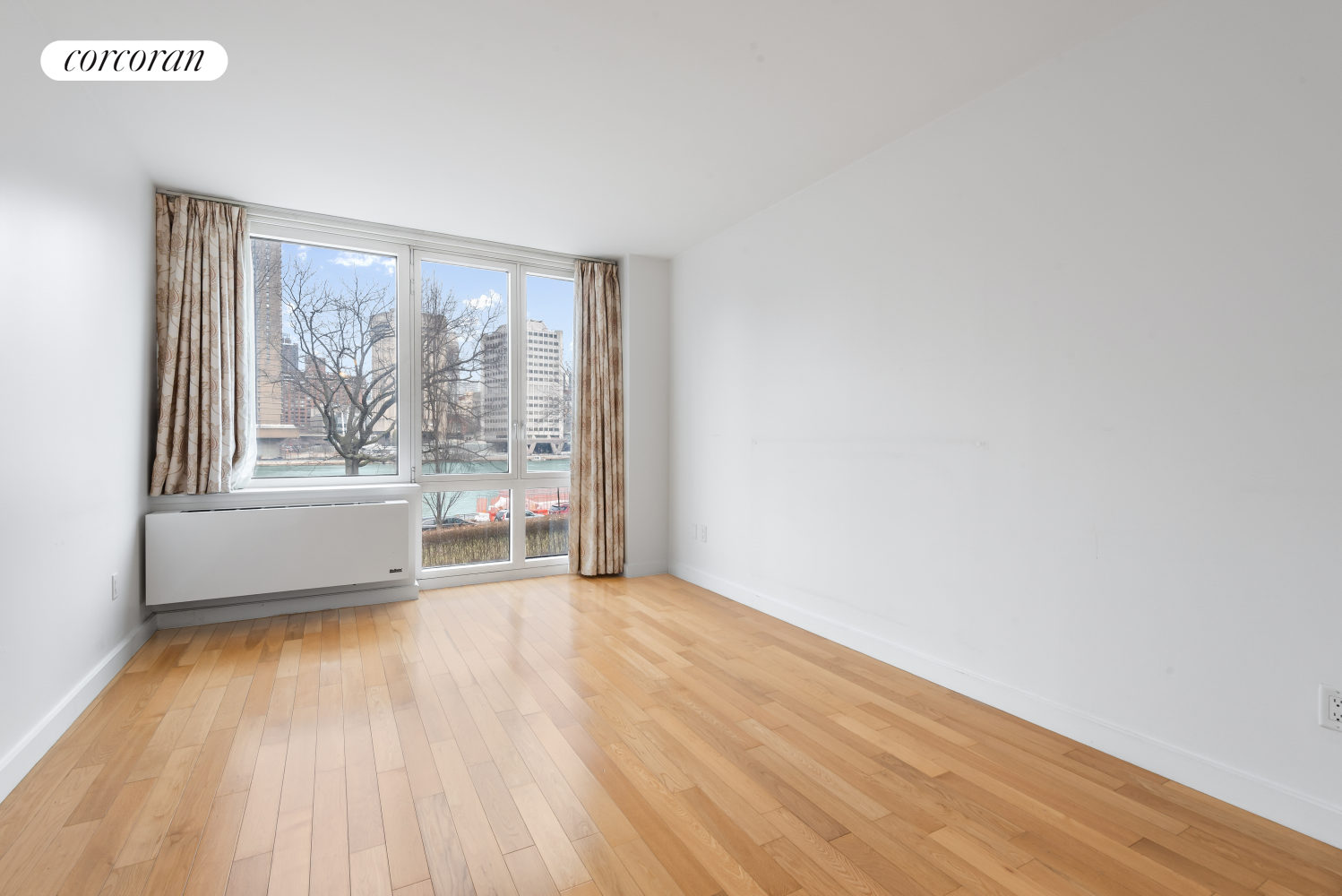 415 Main Street, Unit 2F Manhattan, NY 10044 - Photo 11 of 18 a view of an empty room with a window and wooden floor