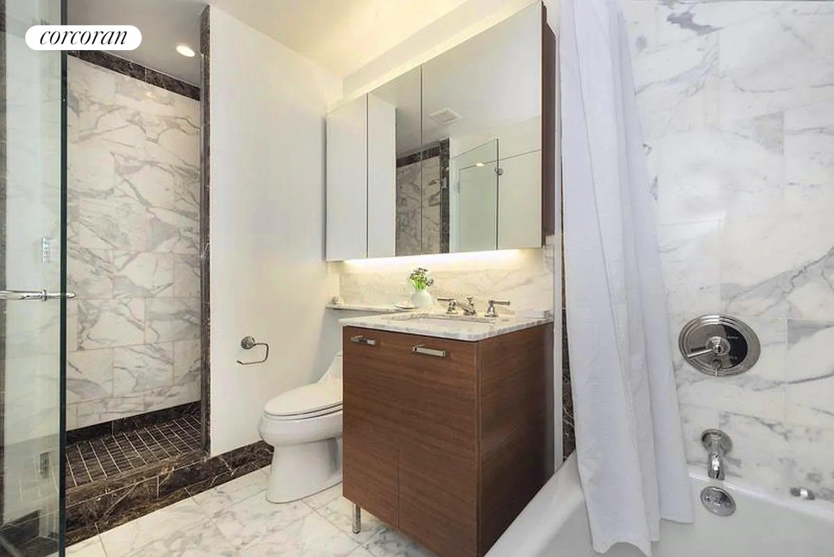 415 Main Street, Unit 2F Manhattan, NY 10044 - Photo 12 of 18 a bathroom with a granite countertop sink toilet and shower