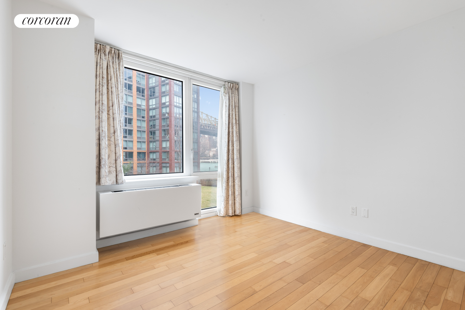 415 Main Street, Unit 2F Manhattan, NY 10044 - Photo 15 of 18 a view of an empty room with wooden floor and a window