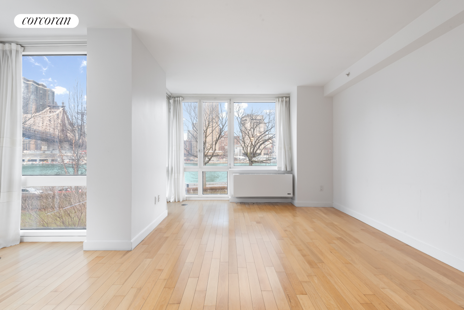 415 Main Street, Unit 2F Manhattan, NY 10044 - Photo 6 of 18 a view of an empty room with wooden floor and a window