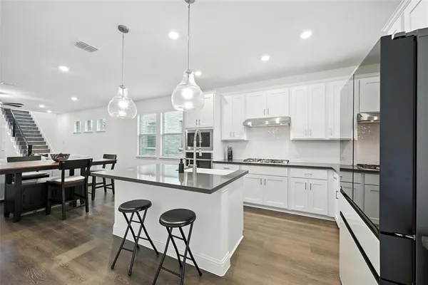 a large kitchen with kitchen island a dining table chairs and white cabinets