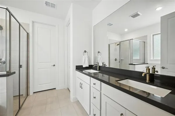a large bathroom with a granite countertop double vanity sink and mirror