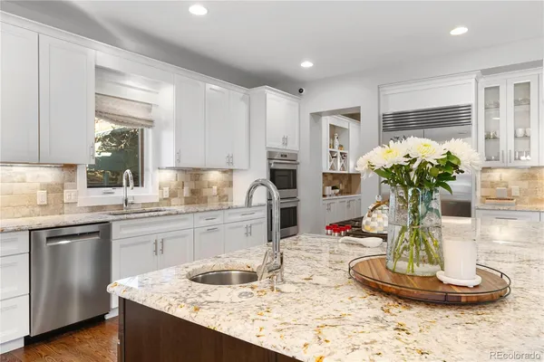 a kitchen with kitchen island granite countertop a sink a stove and cabinets