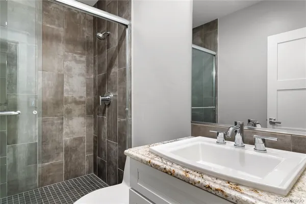 a bathroom with a granite countertop sink a toilet and shower
