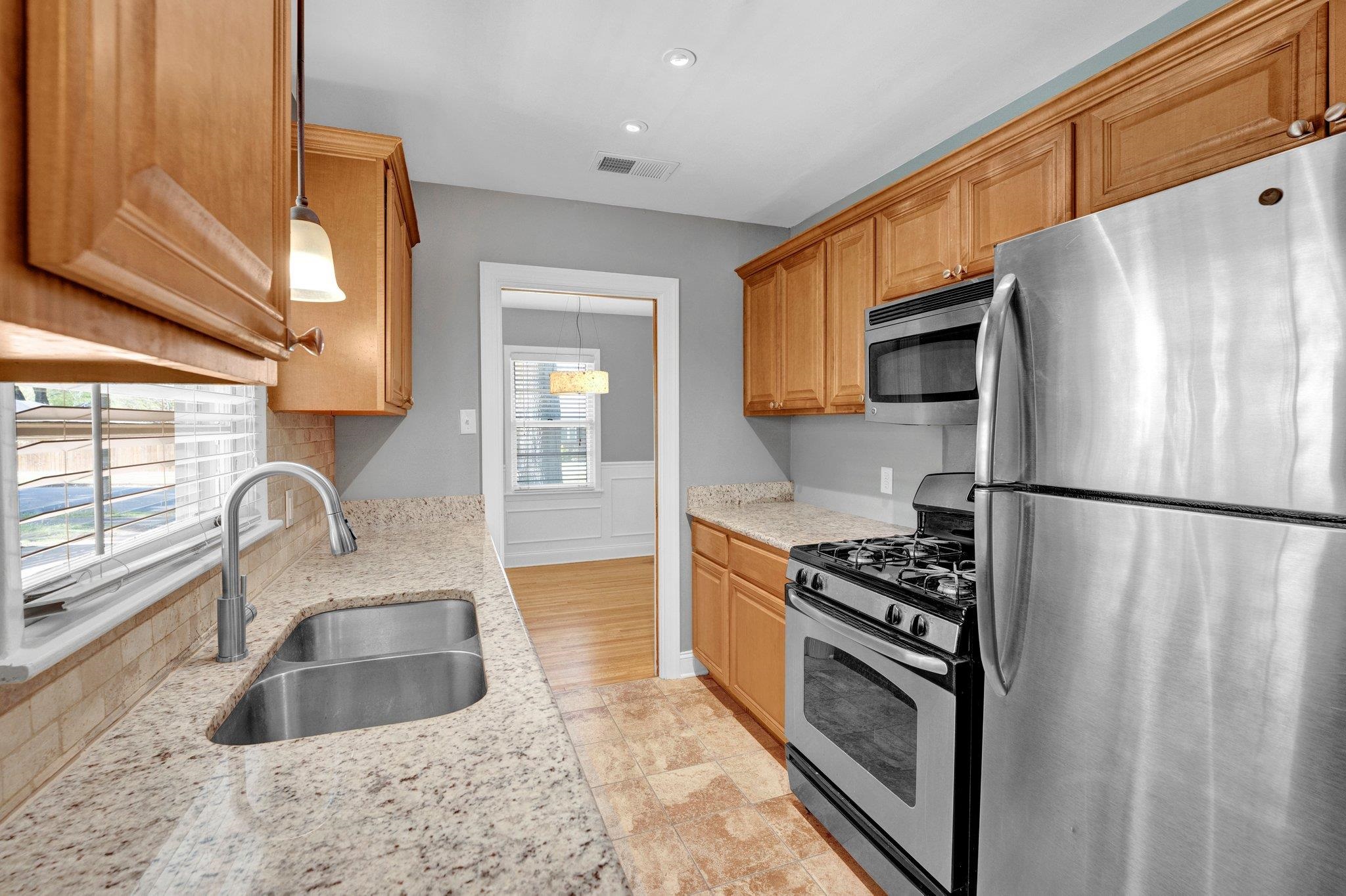 5176 Verne Road Memphis, TN 38117 - Photo 11 of 28 Kitchen with hanging light fixtures, a sink, light stone countertops, backsplash, and stainless steel appliances