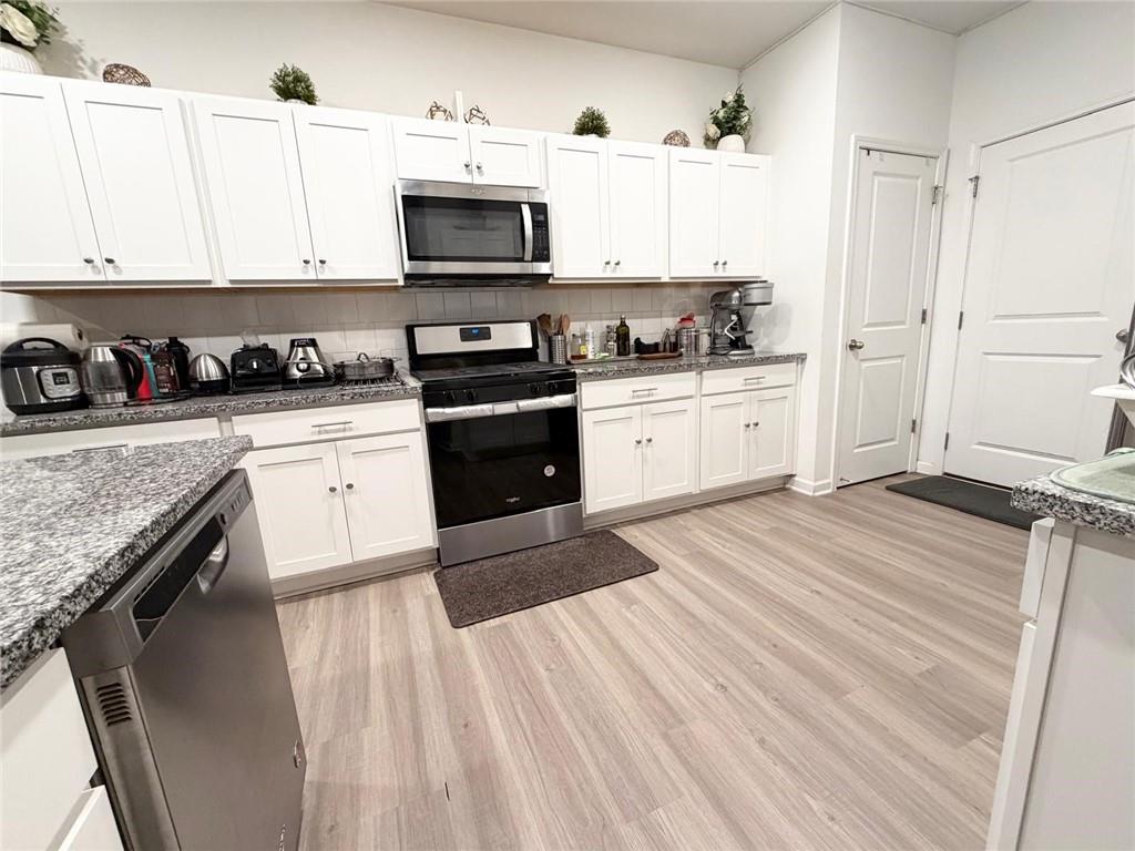 5790 Flint Lane Cumming, GA 30028 - Photo 12 of 40 a kitchen with stainless steel appliances granite countertop a stove top oven a sink and white cabinets