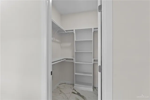 a room with walk in closet with empty racks