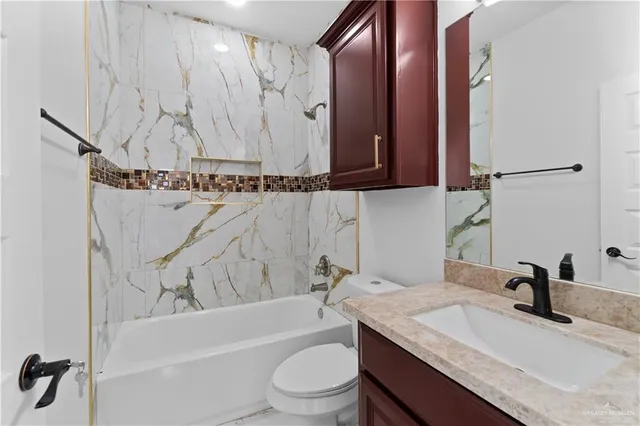 a bathroom with a granite countertop sink a toilet and bathtub