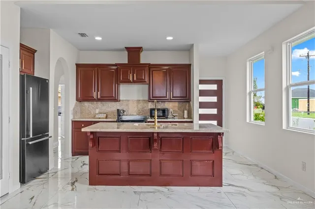 a kitchen with kitchen island granite countertop wooden cabinets and a refrigerator