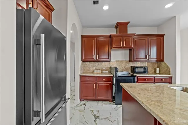 a kitchen with stainless steel appliances granite countertop a refrigerator a sink and wooden cabinets
