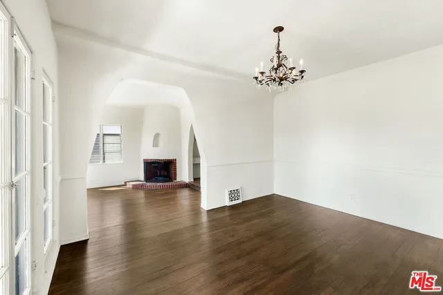 an empty room with wooden floor and chandelier