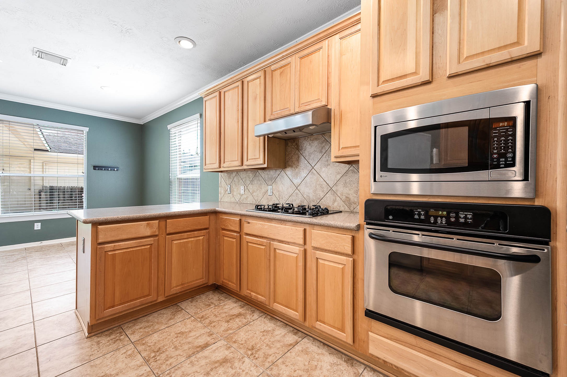 6411 Greencreek Meadows Lane Spring, TX 77379 - Photo 17 of 39 a kitchen with granite countertop a stove top oven microwave and cabinets