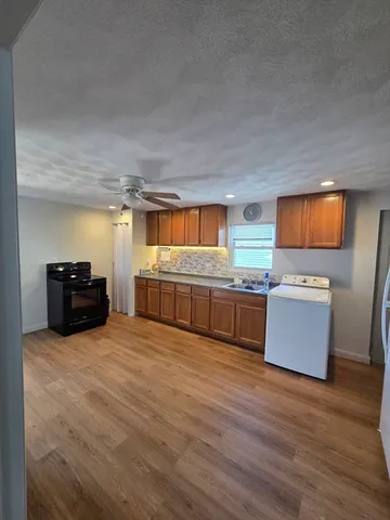 a large kitchen with kitchen island granite countertop wooden floors and a sink