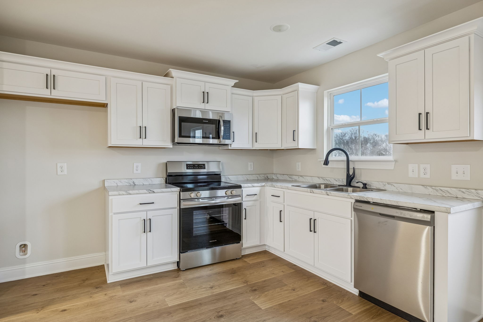 1073 Landing Lane Adams, TN 37010 - Photo 10 of 28 a kitchen with stainless steel appliances granite countertop white cabinets a sink a stove a refrigerator and microwave with wooden floor