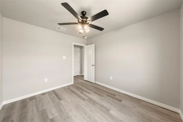 an empty room with a ceiling fan and wooden floor