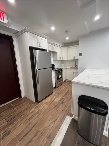 a kitchen with a refrigerator a stove top oven and wooden floor