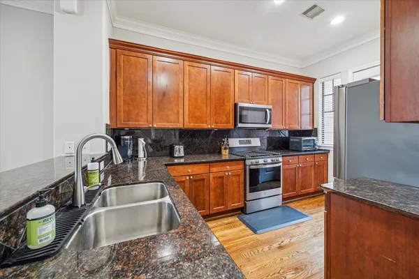 a kitchen with stainless steel appliances granite countertop a stove a sink a granite counter tops and a view of living room