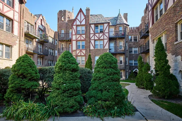 a front view of a multi story residential apartment building with yard and green space