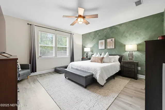 a bedroom with a bed painting on wall and windows