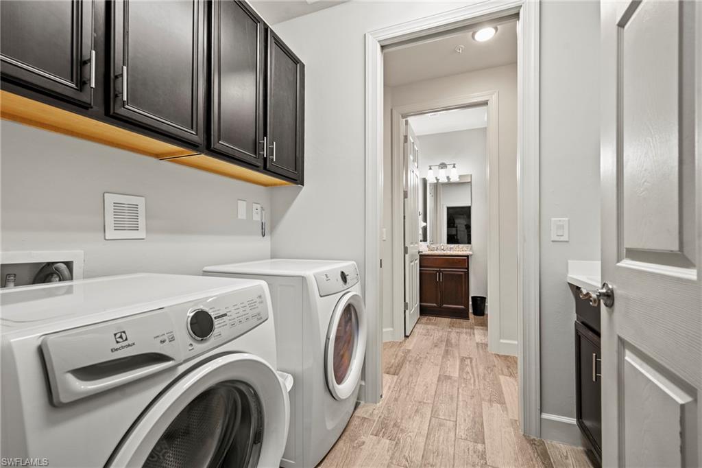 10231 Glastonbury Circle, Unit 101 Fort Myers, FL 33913 - Photo 24 of 35 a view of washer and dryer with kitchen in the background