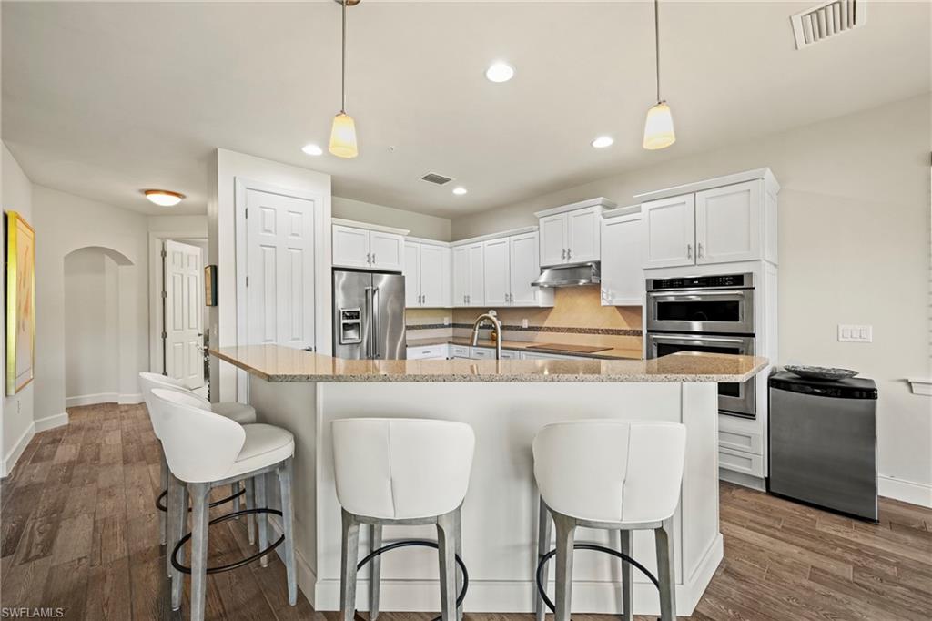 10231 Glastonbury Circle, Unit 101 Fort Myers, FL 33913 - Photo 3 of 35 a kitchen with stainless steel appliances granite countertop a stove a refrigerator a sink a dining table and chairs with wooden floor