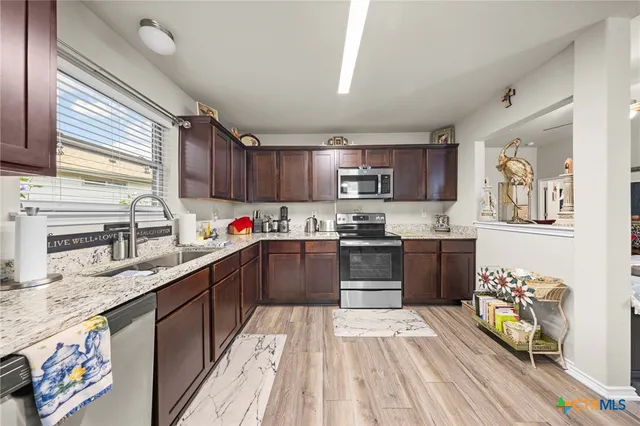 a kitchen with stainless steel appliances granite countertop a sink dishwasher stove and wooden cabinets