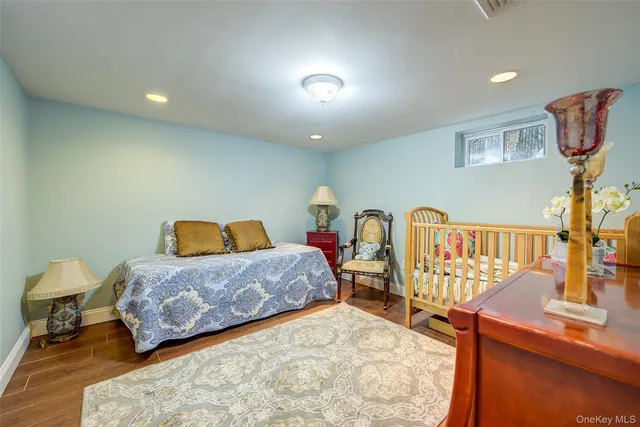 a bedroom with a bed a lamp and wooden floor