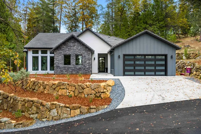 a front view of a house with large trees
