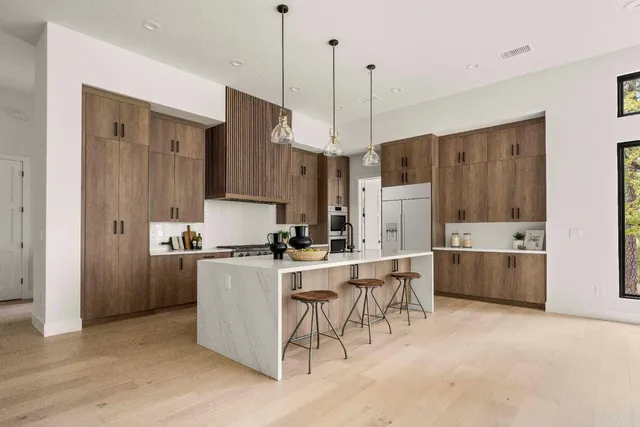 a kitchen with kitchen island a stove a refrigerator a center island a stove and a wooden floor