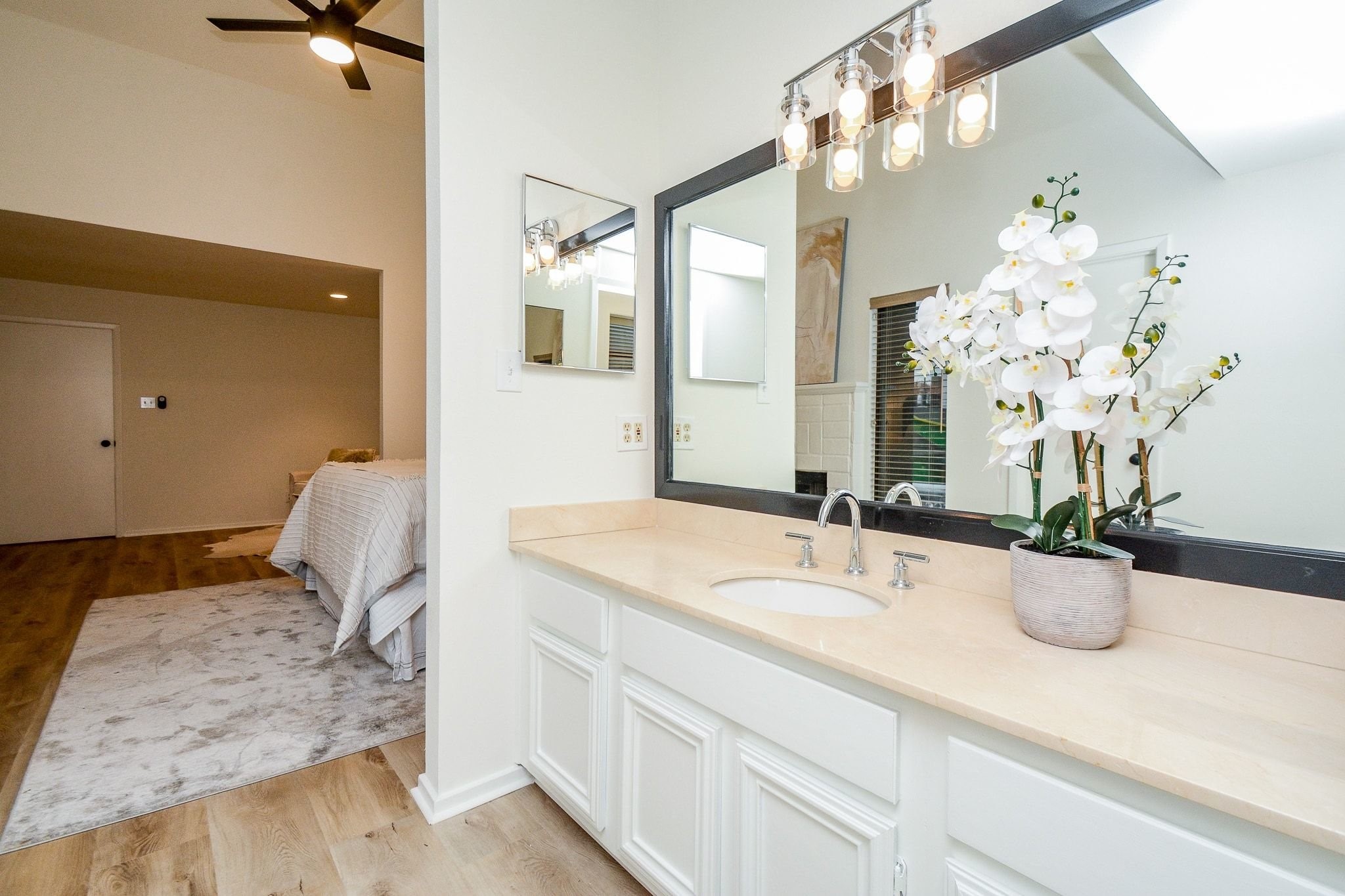 820 Harold Street Houston, TX 77006 - Photo 22 of 33 The en suite vanity opens directly to the primary bedroom, with a large dark framed mirror, pendant style lighting, and warm stone countertops.