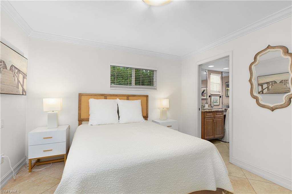 445 3rd Avenue South, Unit 102 Naples, FL 34102 - Photo 17 of 22 a bedroom with a bed and a large mirror on the dresser