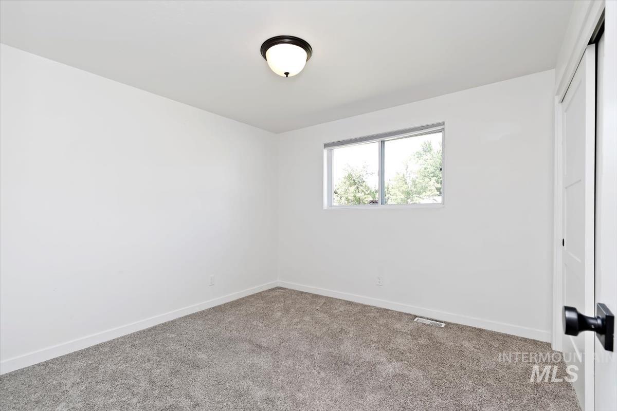 2217 North Middlefield Road Boise, ID 83704 - Photo 22 of 34 Bright room featuring neutral gray carpeting, white walls, a single window, and a white interior door with black hardware