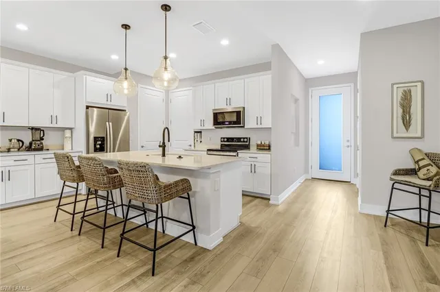 a kitchen with stainless steel appliances granite countertop a refrigerator a stove top oven a sink dishwasher and white cabinets with wooden floor