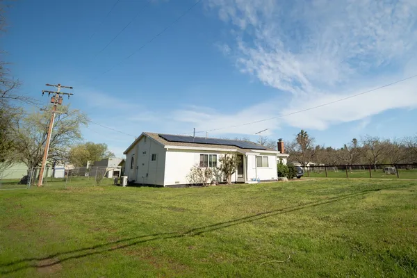 a view of a big house with a big yard and large trees