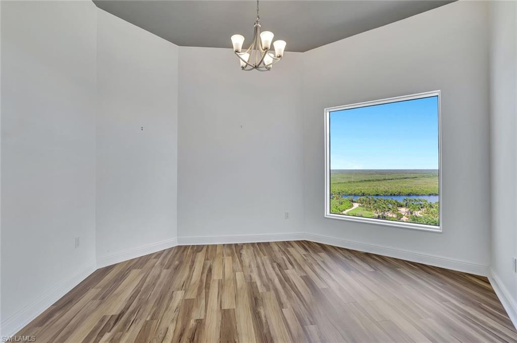 1060 Borghese Lane, Unit 2001 Naples, FL 34114 - Photo 22 of 35 Spare room featuring light wood-type flooring, a chandelier, and a water view