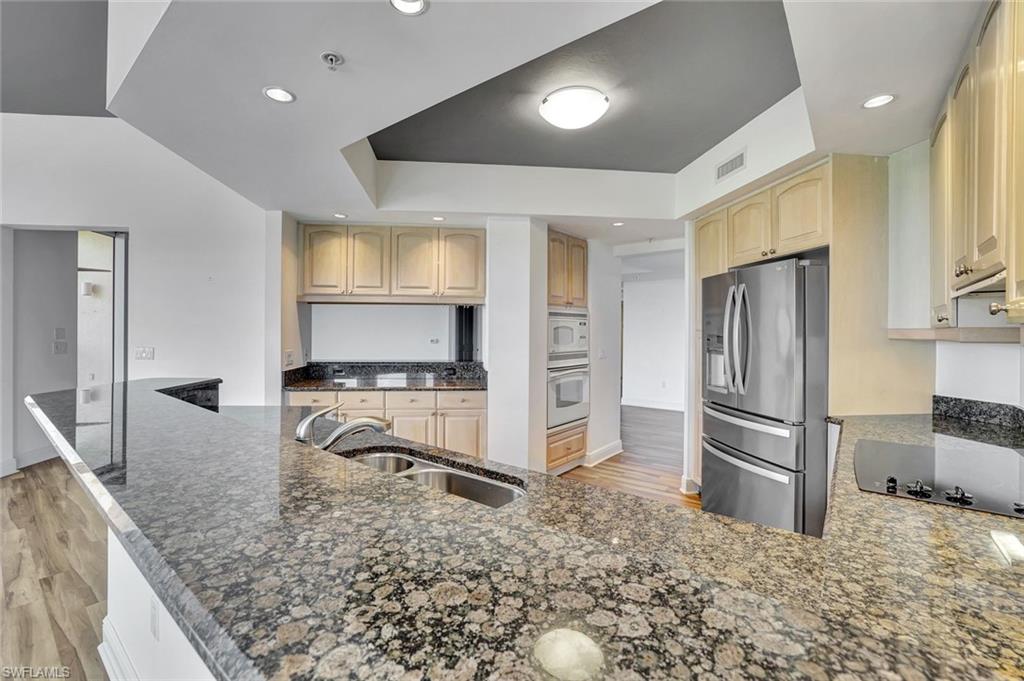 1060 Borghese Lane, Unit 2001 Naples, FL 34114 - Photo 8 of 35 Kitchen with light wood-type flooring, white appliances, dark stone counters, a peninsula, and recessed lighting