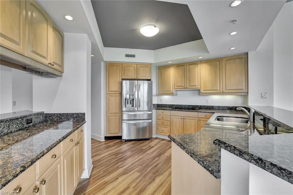 1060 Borghese Lane, Unit 2001 Naples, FL 34114 - Photo 9 of 35 Kitchen featuring recessed lighting, stainless steel fridge with ice dispenser, dark stone countertops, light wood-style floors, and a raised ceiling