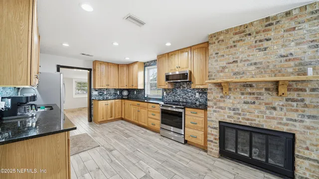 a large kitchen with stainless steel appliances granite countertop a stove sink and cabinets