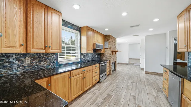 a large kitchen with stainless steel appliances granite countertop a large stove a sink dishwasher and a refrigerator with wooden floor