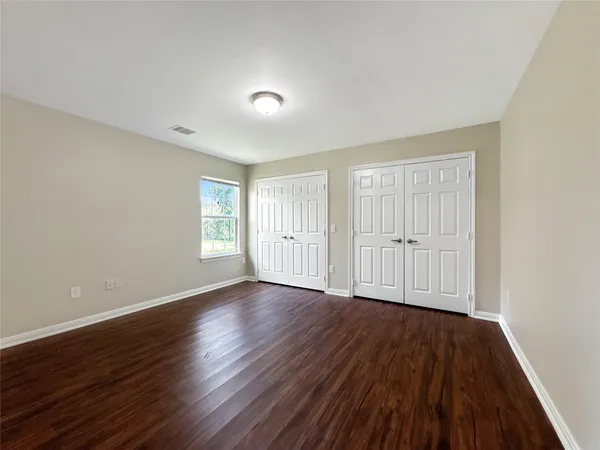 a view of an empty room with wooden floor and window