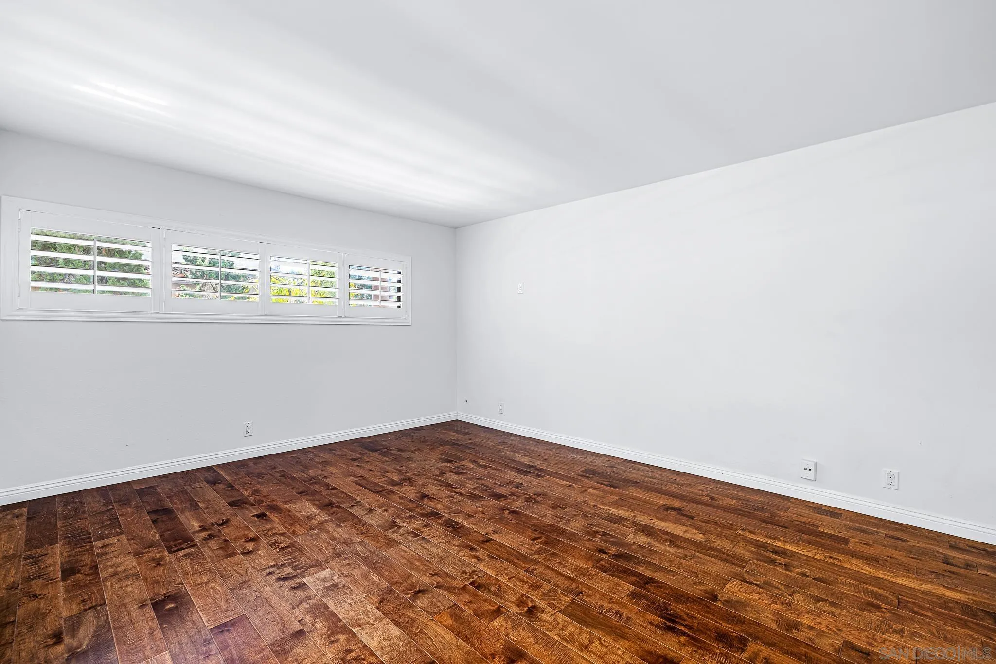 2564 Navarra Drive, Unit 108 Carlsbad, CA 92009 - Photo 10 of 23 an empty room with wooden floor and windows