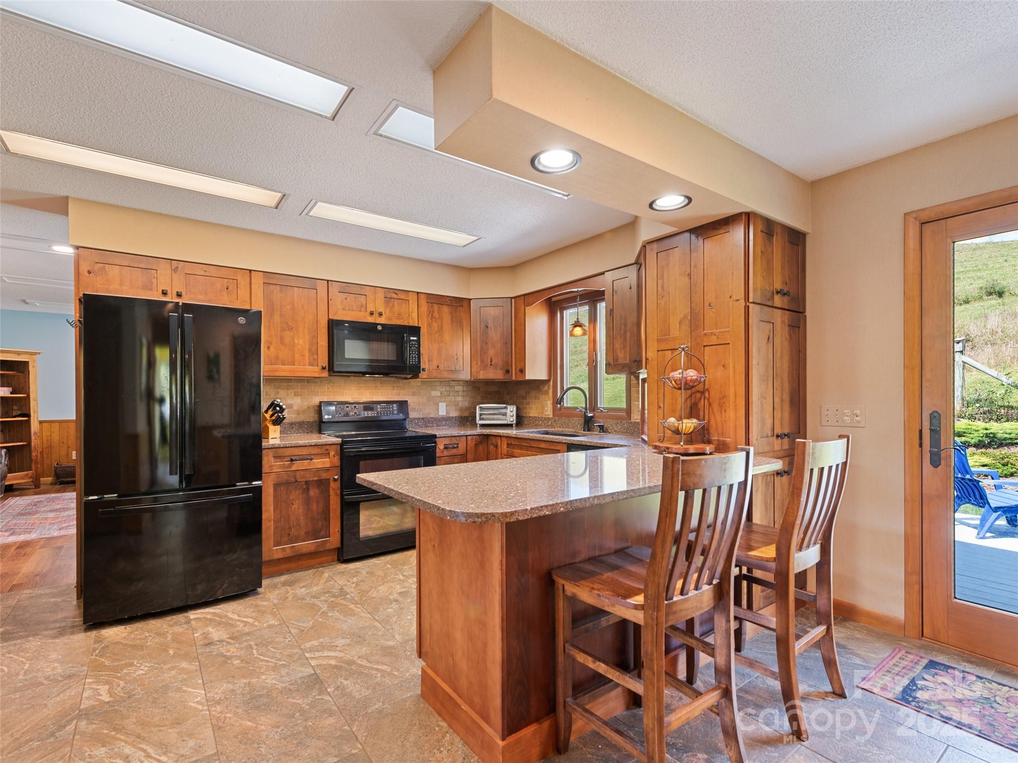 3735 Iron Duff Road Waynesville, NC 28785 - Photo 18 of 48 a kitchen with stainless steel appliances granite countertop a refrigerator a stove a sink a dining table and chairs with wooden floor