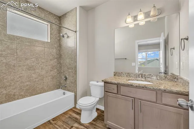 a bathroom with a granite countertop sink toilet a mirror a bathtub and shower