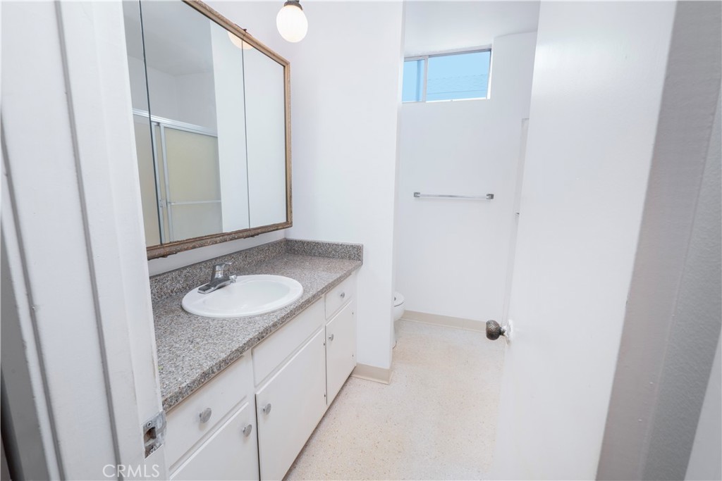 545 Chestnut Avenue, Unit 104 Long Beach, CA 90802 - Photo 30 of 48 a bathroom with a granite countertop sink and a mirror