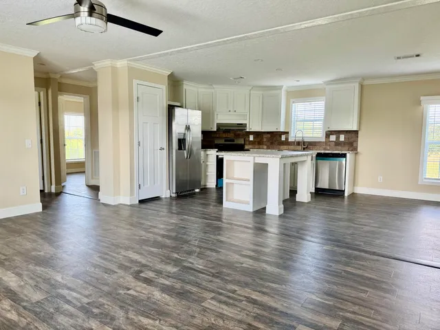 a view of kitchen with stainless steel appliances granite countertop a refrigerator stove top oven and cabinets