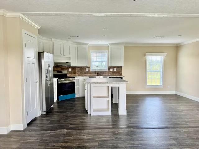 a kitchen with stainless steel appliances a stove a sink white cabinets and wooden floor